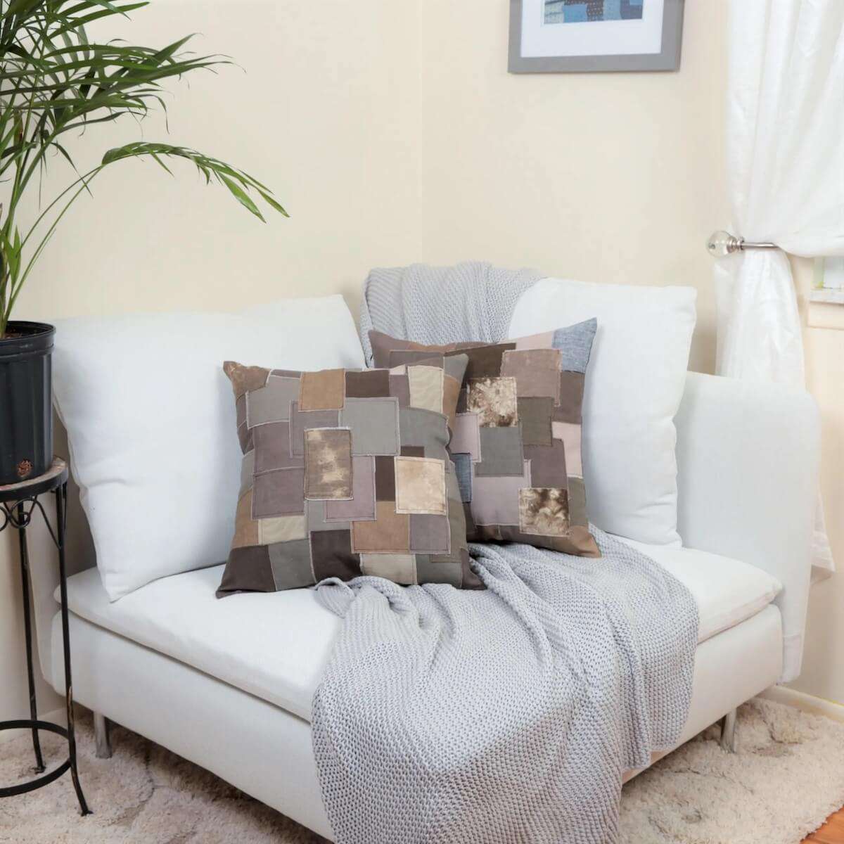 Handmade Japanese boro style patchwork throw pillow cover in warm earth tones arranged on a white sofa.